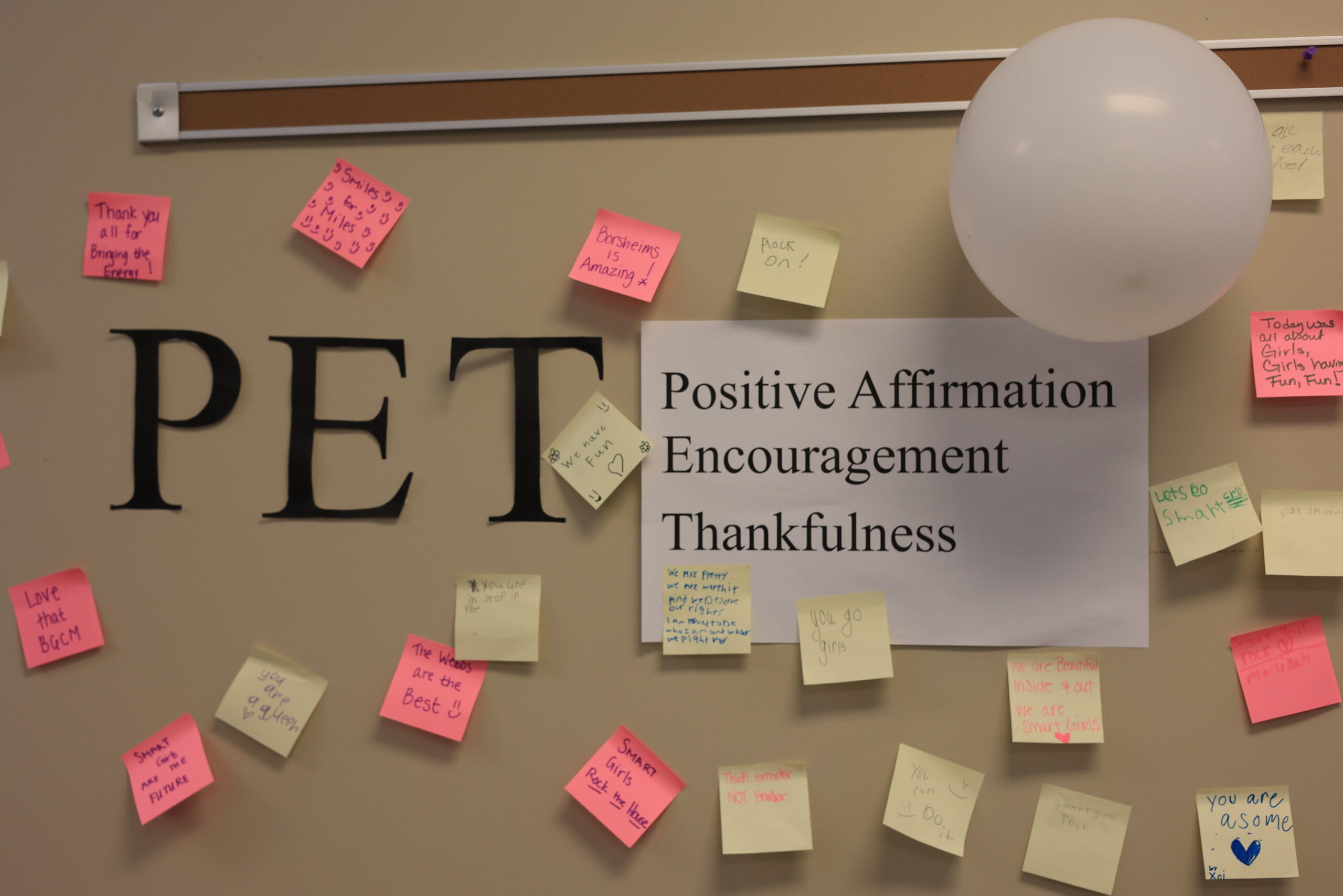 The letters "P" "E" and "T" next to a piece of paper that says Positive Affirmation Encouragement Thuankfulness. Surrounding this are sticky notes featuring positive affirmations written by girls in the SMART girls program