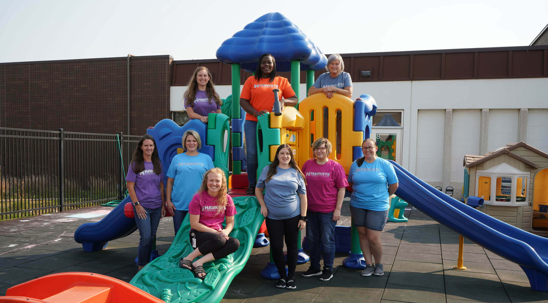 The staff of Hawkeye Community College Foundation Child Care poses for a photo on the playground equipment